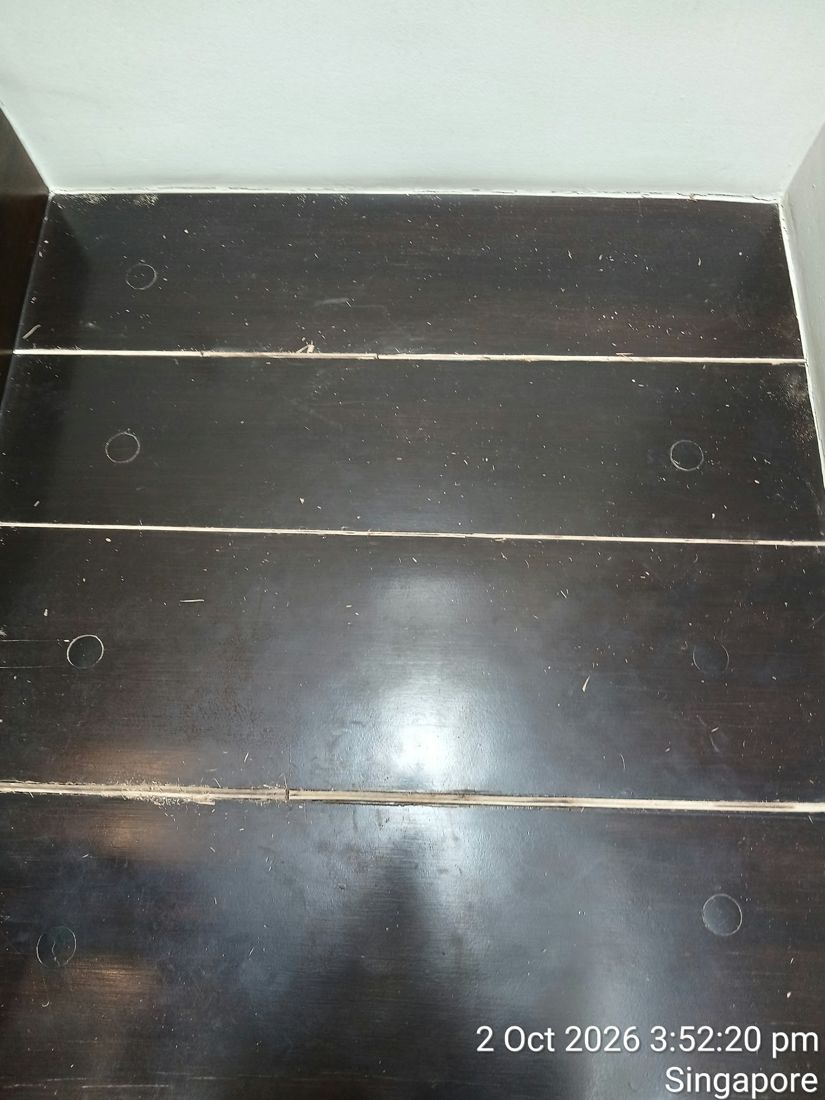 Dark-stained timber boards with open gaps before repair