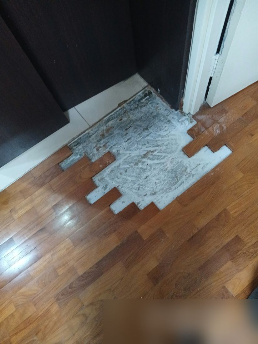 Loose parquet pieces lifted next to built-in cabinets